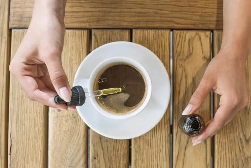 A person adding CBD oil to a cup of tea