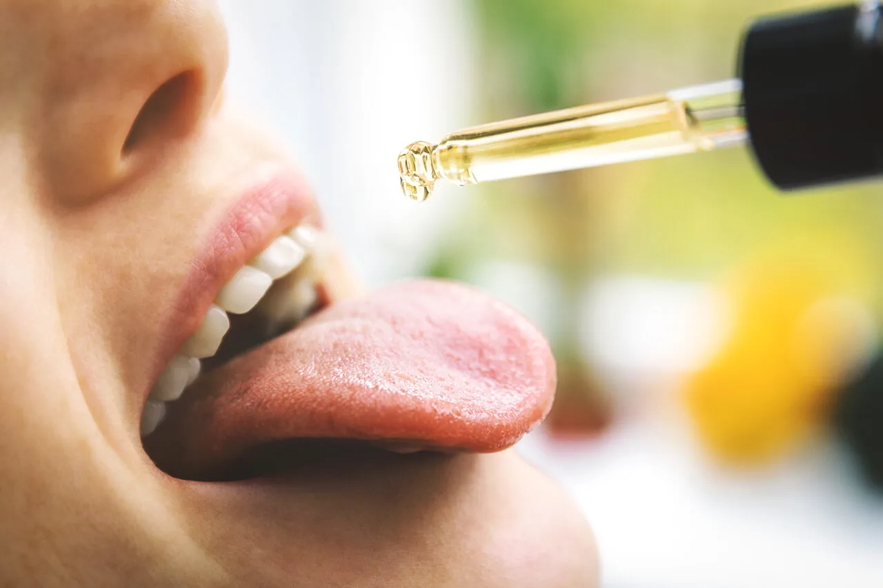 A person placing CBD oil drops under their tongue.